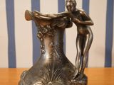 a bronze statue of a woman holding a vase on a table