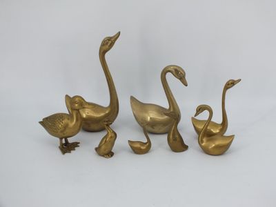 trois figurines de cygnes en laiton sur fond blanc