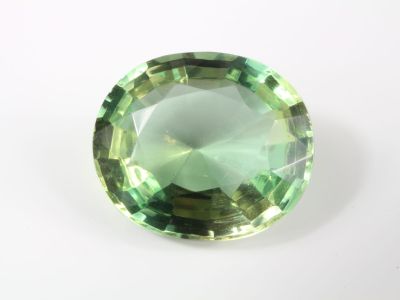 un gros plan d'une pierre précieuse verte sur une surface blanche