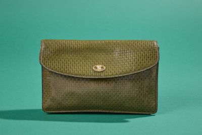 un petit sac à main vert posé sur une surface verte