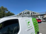 a white van parked in a parking lot with a green sign on the side