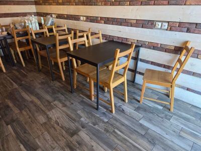 tables and chairs in a restaurant with a brick wall in the background