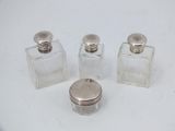 three small glass bottles with silver lids sitting on a white surface