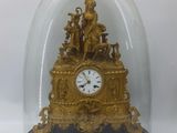 a gold clock under a glass dome on a table