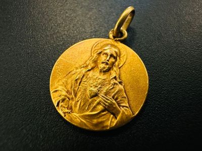a gold medal with a picture of the virgin mary on it
