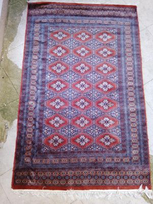 Tapis rectangulaire en laine à fond brique et bordure bleue,…
