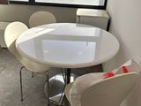 une table et des chaises blanches dans une pièce dotée d'une grande fenêtre
