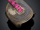a close up of a ring with pink stones on a black surface