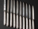 six knives are lined up in a row on a black surface