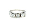 a close up of a three stone diamond ring on a white background