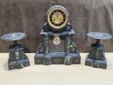 une horloge posée sur une table, à côté de deux tabourets