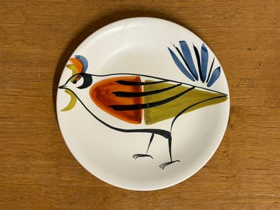 a plate with a bird painted on it on a wooden table