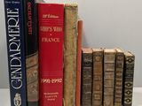 several old books are lined up on a shelf in front of a white wall