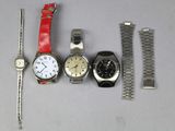 trois montres et un bracelet de montre sont posés les uns à côté des autres