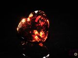 a close up of a heart shaped red diamond on a black surface