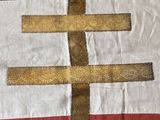 a close up of a flag with a gold cross on it