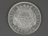 a close up of a silver coin with a cross on it