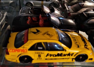 une petite voiture jaune dans une vitrine, à côté d'autres petites voitures