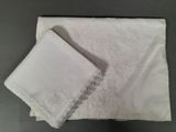 two pieces of white cloth with lace on them on a table