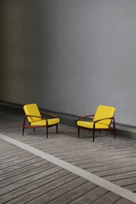 two yellow chairs sitting on a wooden floor next to a white wall