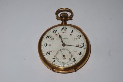 une montre de poche en or sur une surface blanche