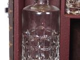 a glass bottle and two glasses in a case
