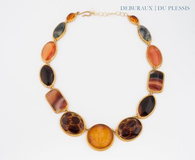 necklace with multi colored stones on a gold chain on a white background