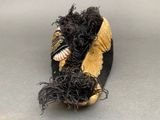 pair of black and gold slippers with feathers on a gray surface
