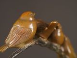 statue of two birds sitting on a branch with a gray background