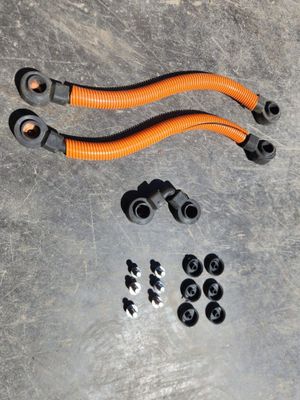 deux tuyaux orange et quelques tuyaux noirs posés sur une surface métallique