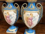 une paire de vases bleus et blancs posés sur une table, avec un tableau en arrière-plan