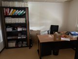 a desk with a chair and a book shelf in the corner