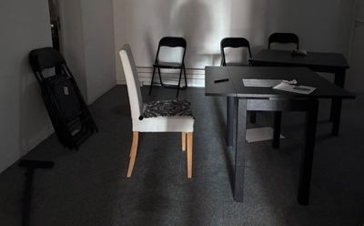 une table et des chaises dans une pièce où se trouve une guitare posée par terre