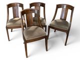 four wooden chairs with brown upholstered seats and a white background