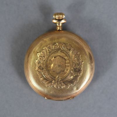 a gold pocket watch on a gray surface