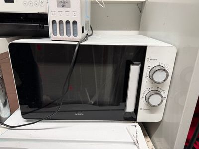 un micro-ondes posé sur une machine à laver et un sèche-linge