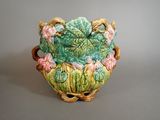 a green vase with pink flowers in it on a table