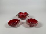 three red glass bowls and a bowl on a white surface