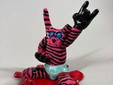 a pink and black cat figurine sitting on top of a blood covered floor