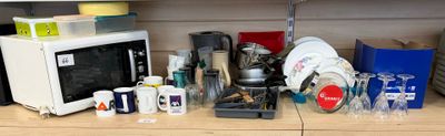 un plan de travail encombré, avec un micro-ondes, un grille-pain, des tasses et d’autres objets ménagers