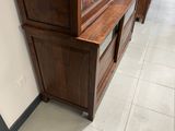 une grande armoire en bois surmontée d'une porte vitrée