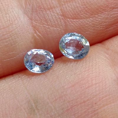 someone is holding a pair of blue and pink gems in their hand