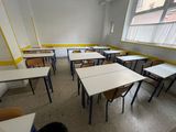 tables and chairs in an empty classroom with a window in the background
