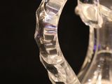 a clear glass vase with a curved handle on a black surface