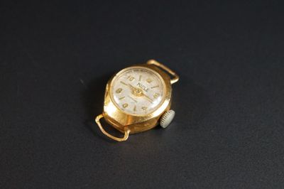 une image représentant une montre-bracelet en or posée sur une surface noire