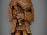 wooden statue of a man with a hat and holding a dog