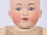 a close up of a baby doll with a sweater on