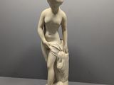 une statue en marbre blanc représentant une femme tenant un sac