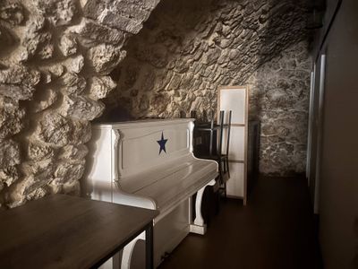 a white piano in a room with a stone wall