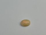 an oval yellow oplite stone on a white surface